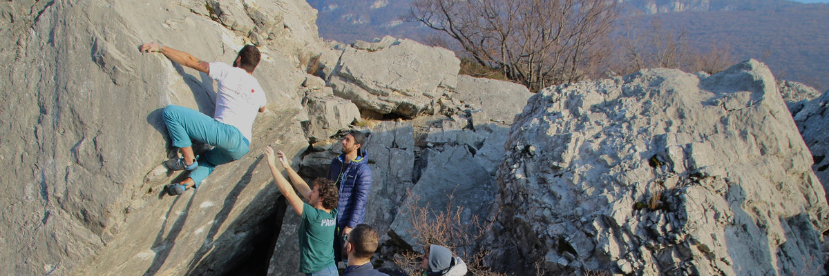 Arrampicatori su un boulder con spotter e crash pad - prevenzione infortuni FisioRock